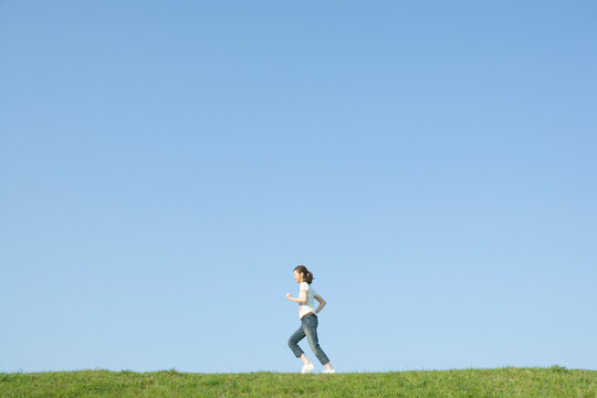 青空の下で走る女性