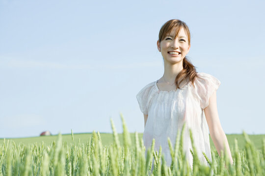 麦畑にたたずむ笑顔の20代女性