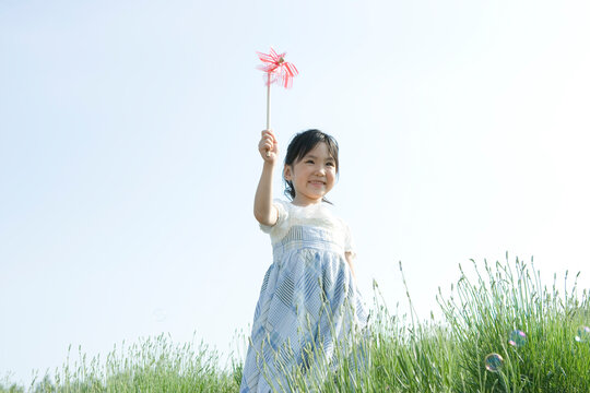 風車を持って走る5歳の女の子