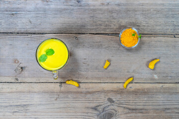 Golden milk in a glass cup on a wooden background