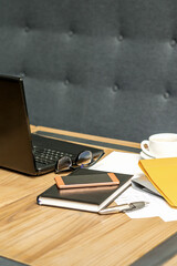 Office workplace with laptop, cup of coffee and paperwork without people.