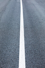 long lonely old asphalt road vertical background with a white solid stripe