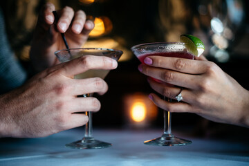 Hands holding cocktails at a bar