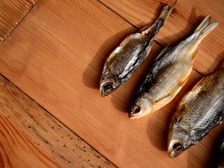 three dry salted river fish on a wooden board, copy space