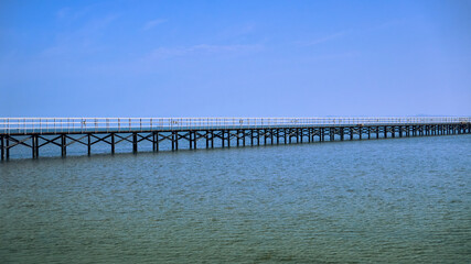 Fototapeta na wymiar bridge on the shore of the beautiful sea goes to the horizon