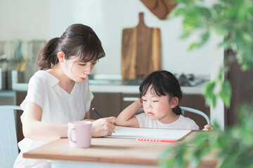 ダイニングテーブルでお絵かきをするお母さんと娘