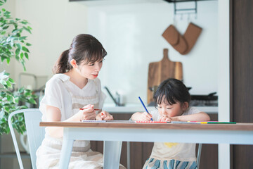 ダイニングテーブルでお絵かきをするお母さんと娘