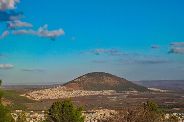 Beautiful view of Mount Tabor and the surrounding countryside in Israel. Lower Galilee in northern Israel with modern agricultural fields in the foreground. Biblical Mount Tabor and the Arab village.