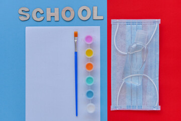 Study flatlay concept. Education supplies-brush, paint, medical mask and sanitizer on blue, white and red background,back to school or kindergarten. summertime, creativity and learn background