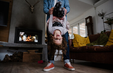 Fototapeta na wymiar Young Caucasian daughter playing with father in the lounge, upside down