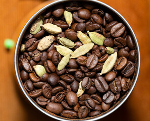 Black coffee beans and Green cardamom pods. Grinding raw materials for a drink in a coffee grinder.