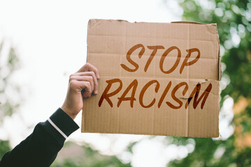 Young man holding racism cardboard in hands