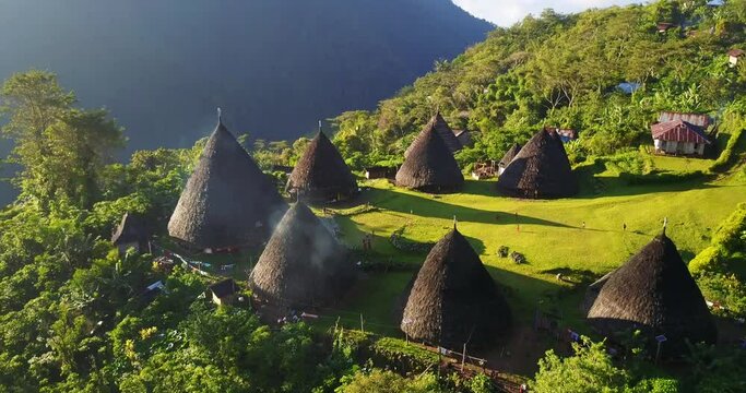 Wae Rebo traditional village on Flores island, an Unesco heritage site, down-looking aerial sunny view over the woody houses with villagers walking around, must-see destination in Indonesia and Asia