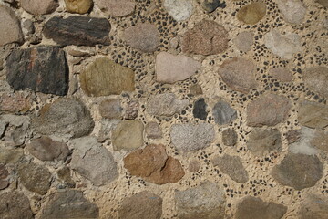 The wall of the building is made of chipped stone on a mortar. Beautiful texture