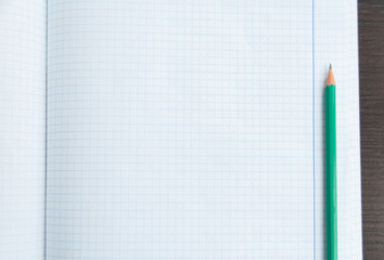 Back to school, education concept. Blank notebook page with a pencil on the wooden table. Design mockup. Copy space. Top view. Flat lay