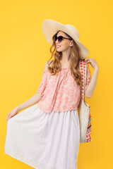 Happy young attractive woman in a summer hat and sunglasses, on an yellow background