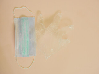 Sanitary mask with plastic glove on cream background with copy