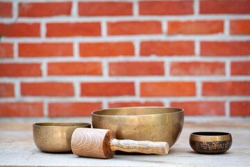 Ancient hand crafted traditional Tibetan meditation and healing singing bowls made from 7 sacred metals which are typical accessories used in buddhism, yoga and meditation, against a red brick wall