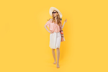 attractive happy young woman in sunglasses and a summer hat, on an yellow background