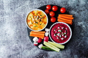 Set of classic hummus and beet hummus appetizers with carrot, radish, tomato and cucumber