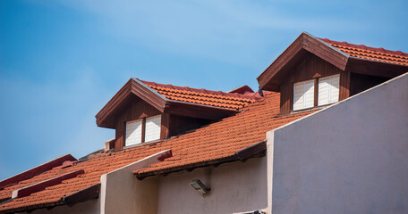 tiled roof with an attic against the blue sky