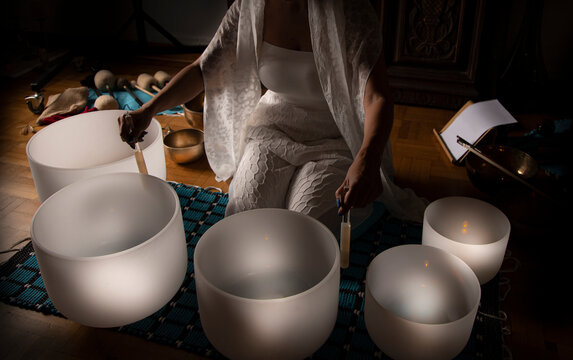 Woman in A serene sound healing therapy session with a practitioner playing crystal singing bowls indoors, promoting relaxation and healing  
