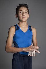 Male child gymnast chalking his hands before competition