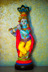 Fototapeta na wymiar Colorful figure of the Hindu God Krishna playing the flute. Lord Krishna playing the flute.