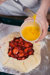 beaten egg in bowls on a background of raw strawberry cake
