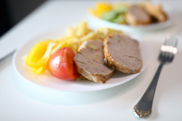 Close-up of yummy bright breakfast. Cucumber tomato slices of meat and fresh yellow pepper. Delicious portion for couple served on white plate with fork. Healthy eating and food concept