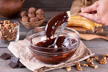 Woman hands pour frozen banana with chocolate. Frozen