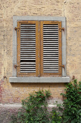 Fototapeta na wymiar ALTE Fassade mit alten geschlossenen Schlagläden in gelb