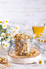 Dried chamomile flowers and wooden spoon on white background. Organic Chamomile Tea in cup
