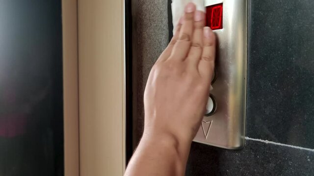Close up of Young female hand cleaning elevator / lift button up & down in Office Center or Hotel with sanitizer and tissue paper due to Coronavirus disease (Covid-19) pandemic. 4K Slowmotion.