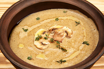 Thick mushroom cream soup in a clay pot. Proper balanced nutrition. Vegetarian vegetable soup. Dish menu on a wooden board. Fragrant hot food. High-calorie food. Organic products. Restaurant menu.
