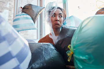 Unkempt Asian woman is scared of tons of garbage bags at her loggia