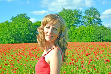 Naklejka na ściany i meble Happy young woman stands in poppy field