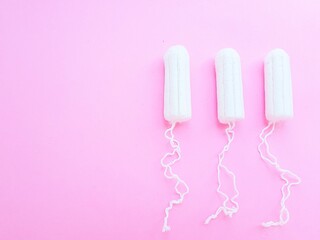 Women's hygiene intimate accessories. A clean white tampon on a pink background. Menstrual cycle. Space for text.