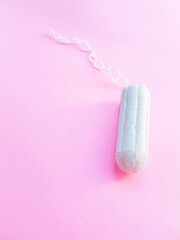 Women's hygiene intimate accessories. A clean white tampon on a pink background. Menstrual cycle. Space for text.