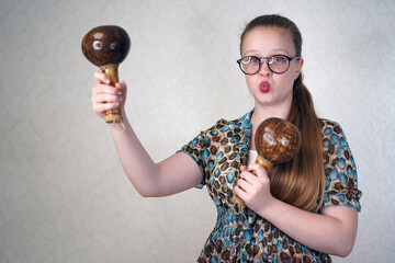 Teen girl holding maracas in her hands. Learning to play musical instruments. A blue-eyed girl  with long hair dancing with maracas. Beautiful charming young girl