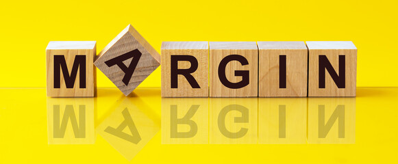MARGIN word made with wooden blocks concept, yellow background.