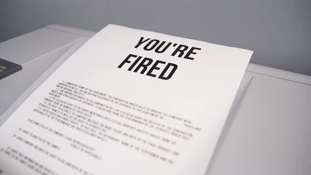 Layoffs, business closures, unemployment. Paper with words YOURE FIRED comes out of office laser printer. Printed a message about dismissal