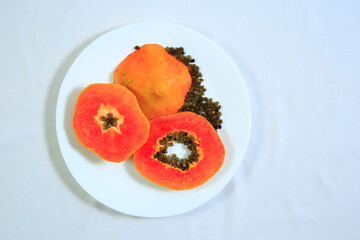 Fresh ripe sweet sliced papaya fruit in a white bowl isolated on white background