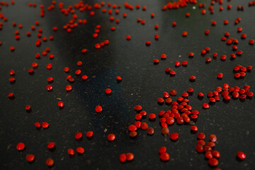 Obraz premium Red sandalwood (Adenanthera pavonina) seeds isolated on a black background. Manchadi, Manjadi, Manjetti, Peacock flower fence, Acacia Coral, Anikundumani, Bandi guruvenda, Barbados pride, Barricarri.