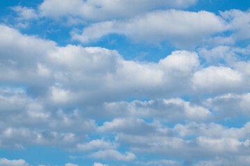 Naklejka na ściany i meble Fluffy white clouds on bright blue sunny sky background. Skyscape natural harmony
