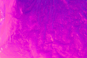 Background from purple recyclable polyethylene in neon pink light. Eco, zero waste, alternative to plastic concept. Flat lay. Horizontal. Closeup