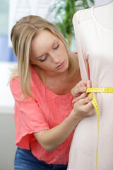 young professional female tailor using tape tool measure