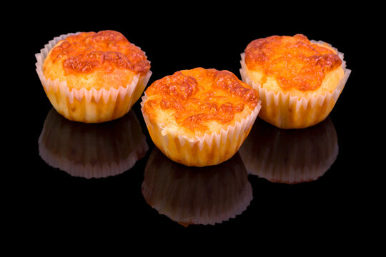 Tasty salt muffins in baking form, isolated on black background, with reflection