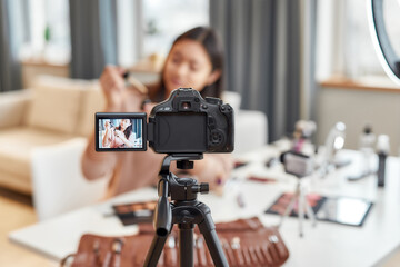 New perspectives. Asian female blogger showing cosmetic products while recording a tutorial video for her beauty blog using camera at home