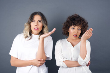 What the hell are you talking about, nonsense. Studio shot of frustrated female with blonde hair gesturing with raised palm, frowning, being displeased and confused with dumb question over gray wall.